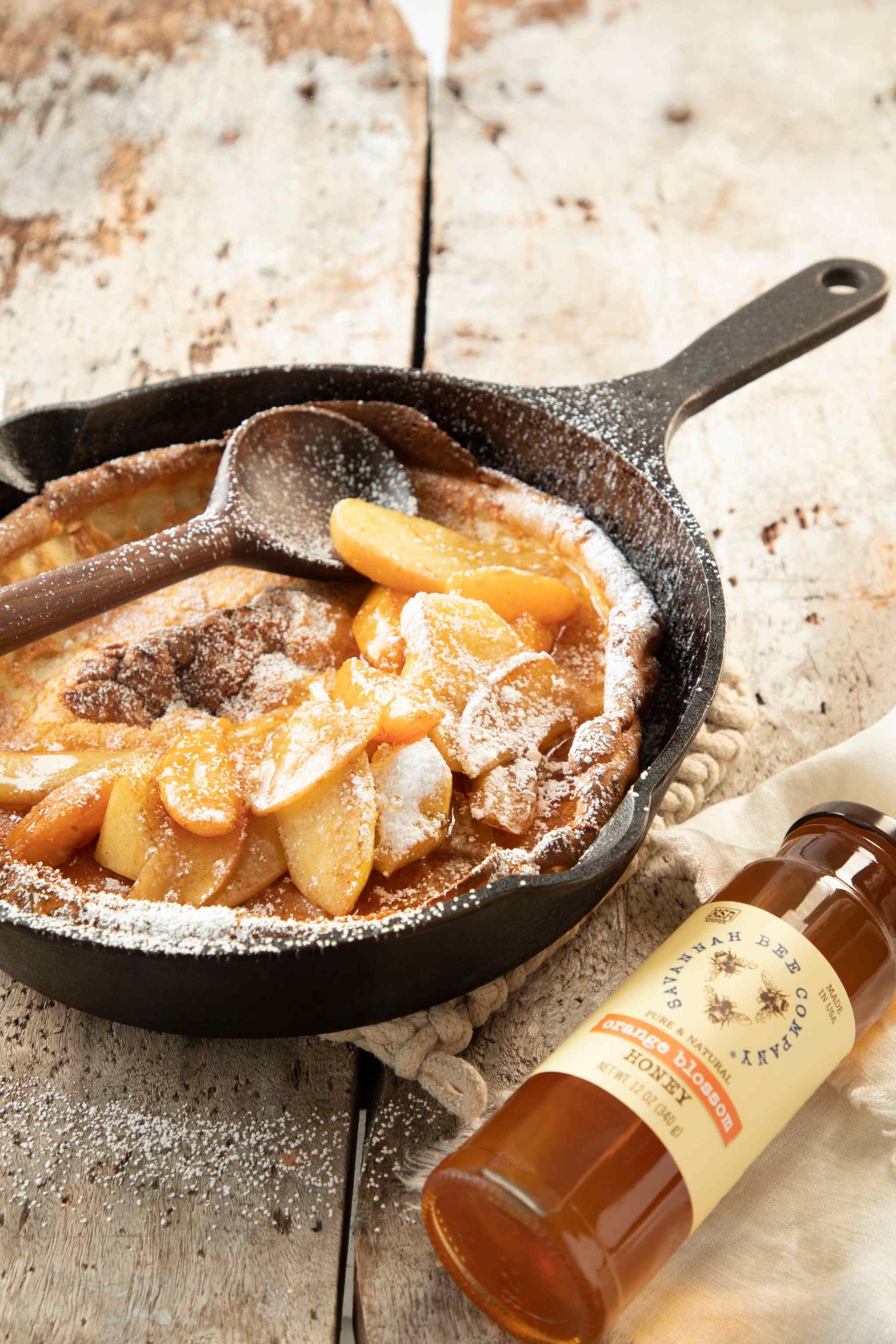 Apple pecan pir in a skillet next to 12 ounce jar of orange blossom honey.
