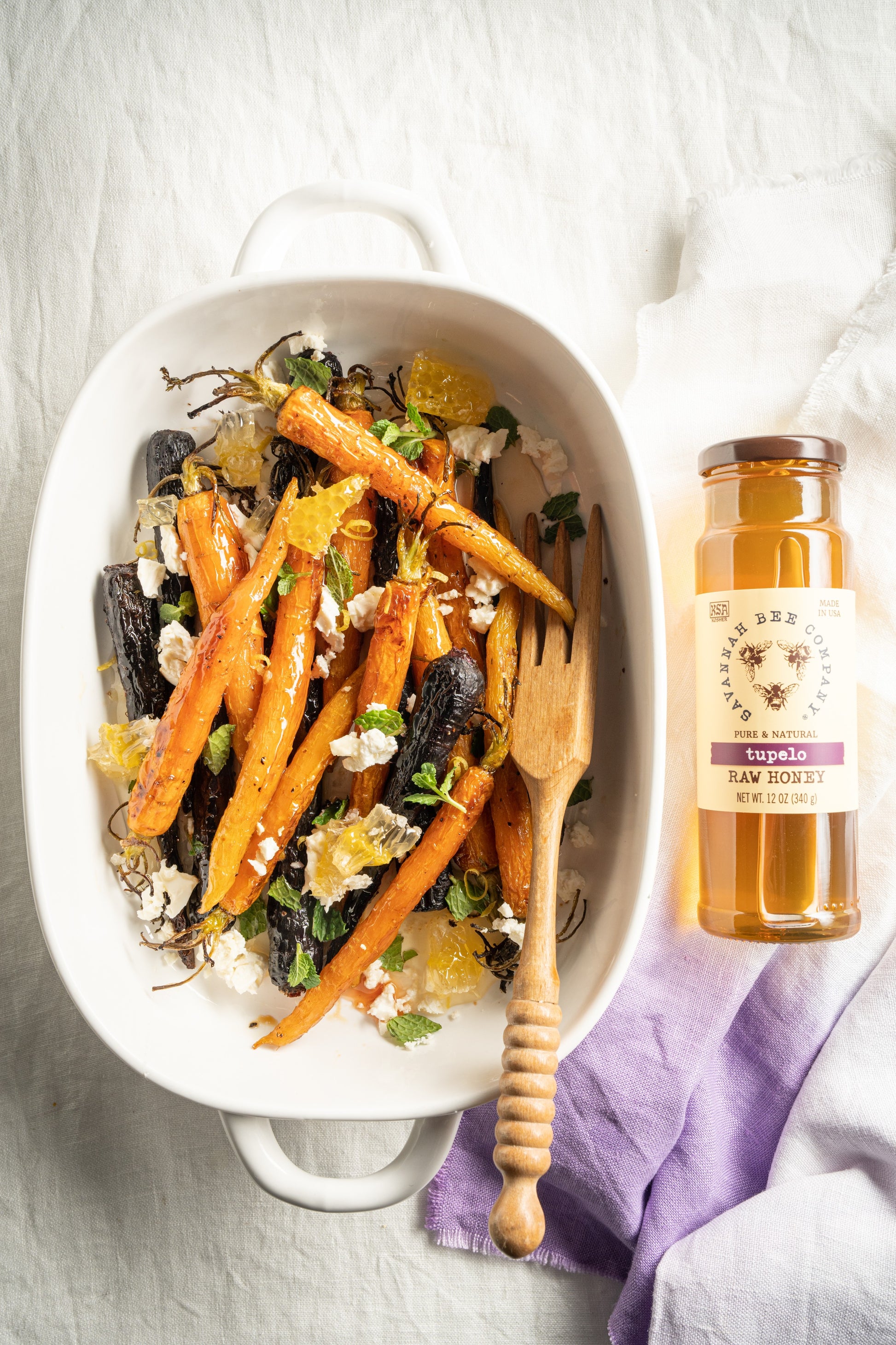 tupelo honey roasted carrots with feta and greens next a bottle of tupelo honey