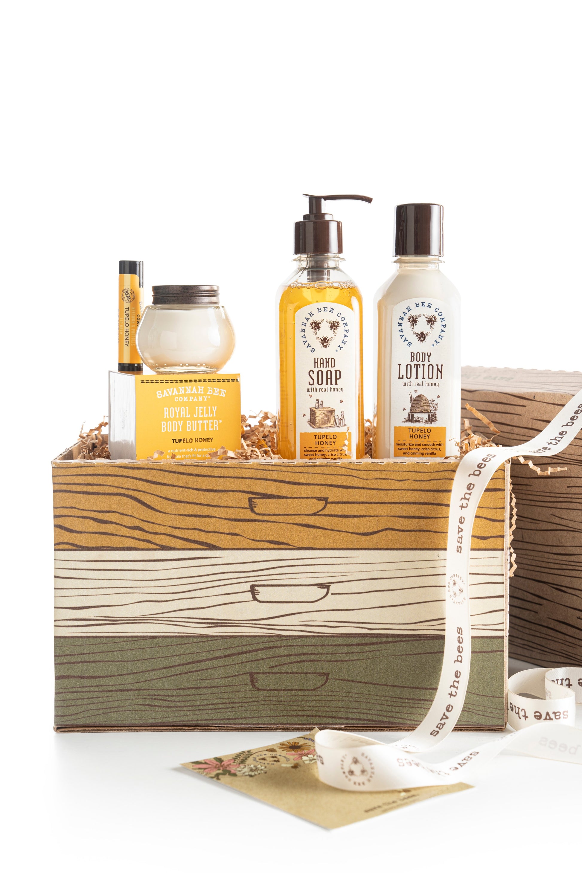 Tupelo Honey Hand Soap, Tupelo Honey Body Lotion, Tupelo Honey Royal Jelly Body Butter, and Tupelo Lip Balm standing in a Save The Bees gift box.
